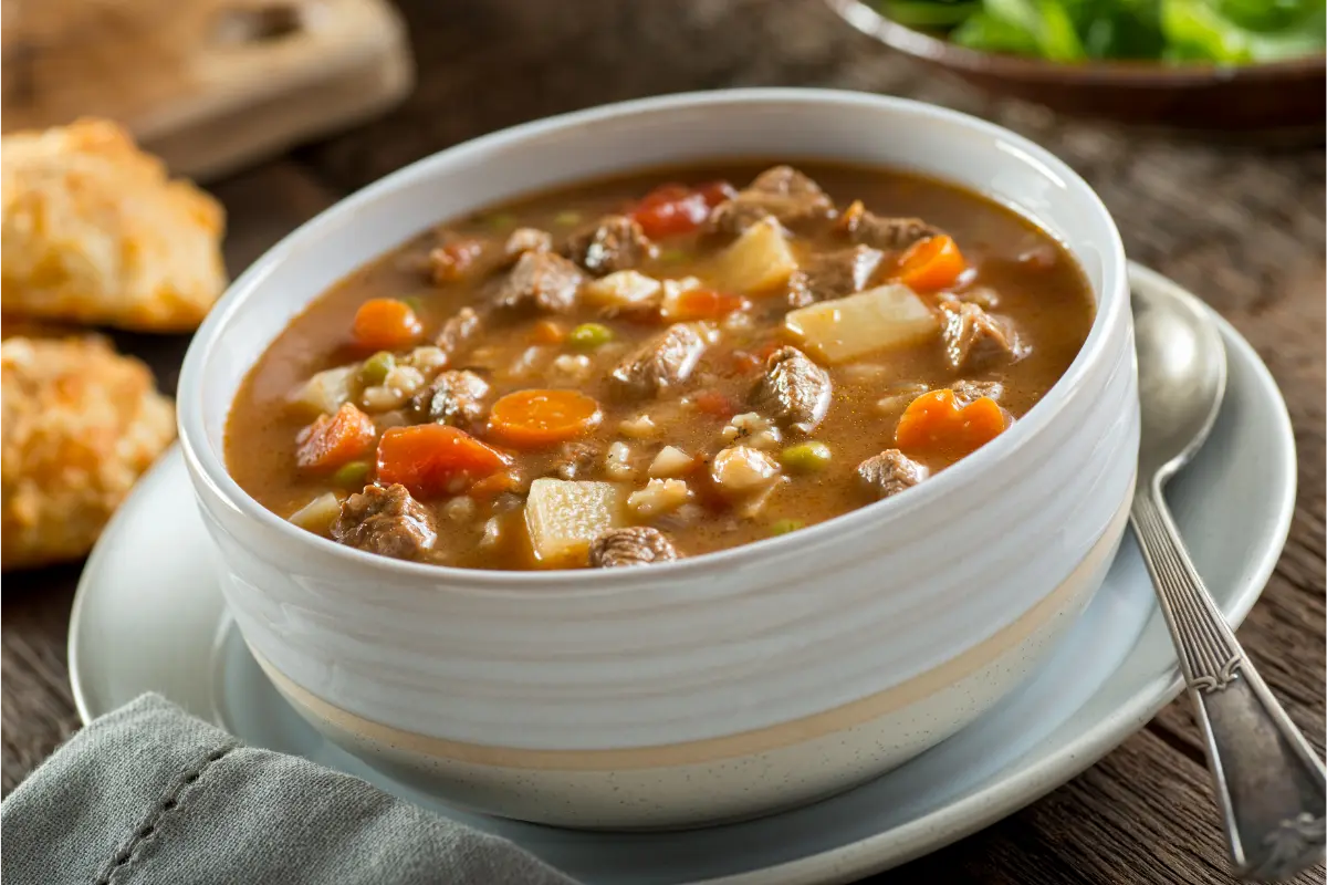 A bowl of Busy Day Soup, laden with hearty ingredients for a comforting and quick meal, presented on an inviting wooden table setting.